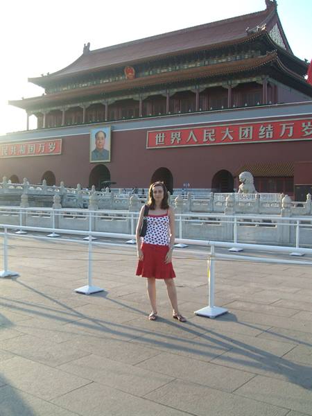 Woman in red dress posing before Mao's portrait at Tiananmen Gate