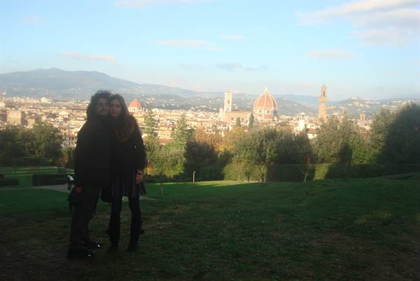 Couple embracing on the grass, Florence cathedral and bell tower behind