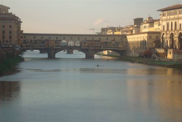 Ponte Vecchio over the Arno in Florence, canoe on the water, golden light on buildings