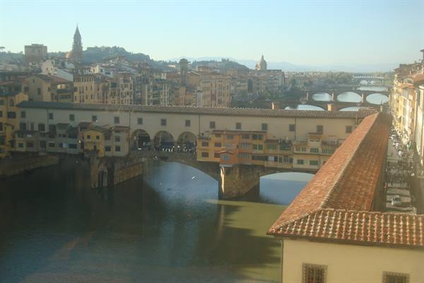 Ponte Vecchio over the Arno river, Florence rooftops under blue sky
