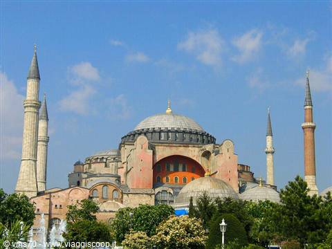 Hagia Sophia in Istanbul, central dome and minarets among trees under blue sky