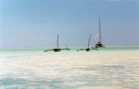 Traditional sailboats anchored in shallow turquoise lagoon under clear sky