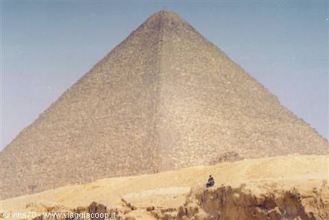 A person sitting on rocks in front of the Great Pyramid of Giza
