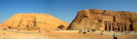 Abu Simbel: two rock-cut sandstone temples under blue sky, tourists walking in front