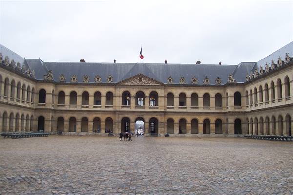 Courtyard of Les Invalides, Paris, stone arcaded facade, French flag, grey sky