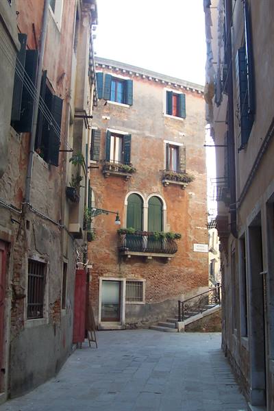 Venice: old houses with shutters and flowered balcony over a quiet alley
