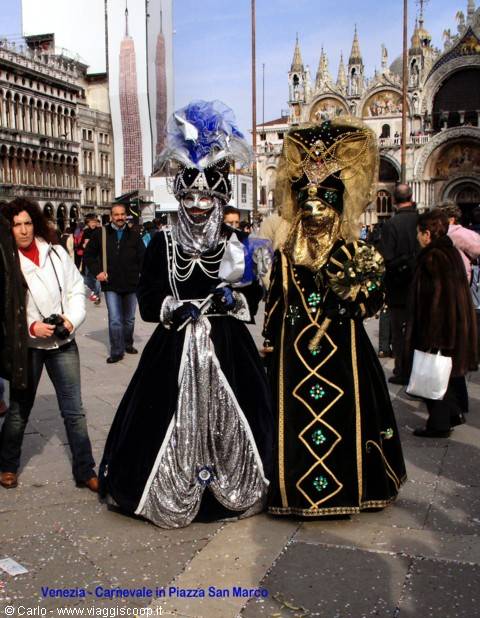 Two black and gold carnival masks pose in St Mark's Square, Venice