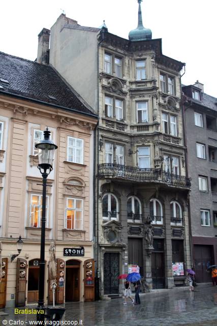 Historic buildings in Bratislava in the rain, pedestrians with umbrellas on wet square