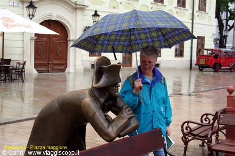 Tourist under an umbrella next to the bronze soldier statue in Bratislava's Main Square
