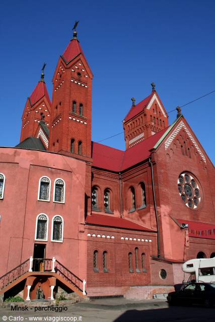 Red brick church with spires, Minsk, blue sky and parked cars