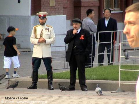 Moscow, Red Square: ceremonial guard in white uniform beside a man wearing a red flower