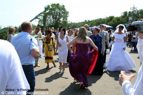 Brides in white gowns and guests celebrating outside Moscow State University