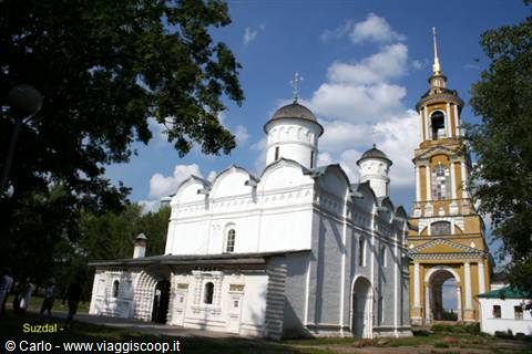 White church with domes in Suzdal, beside the yellow bell tower