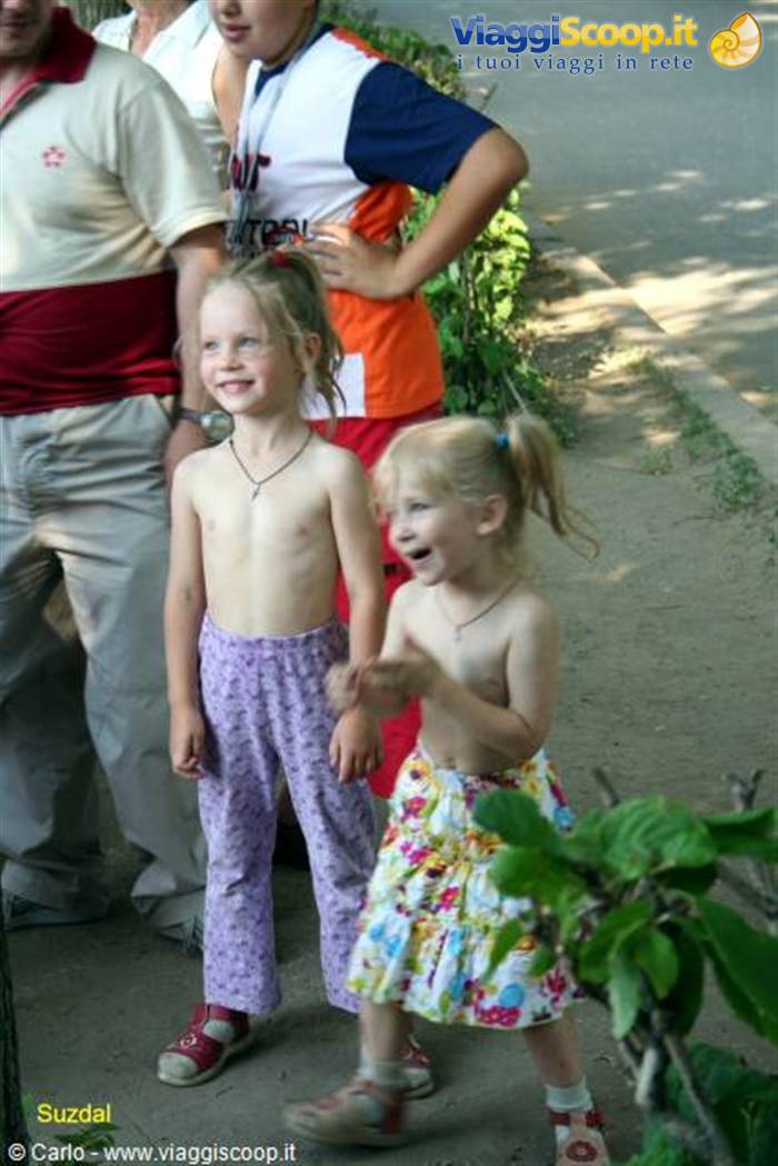Smiling children in summer clothes in Suzdal, among greenery and shade