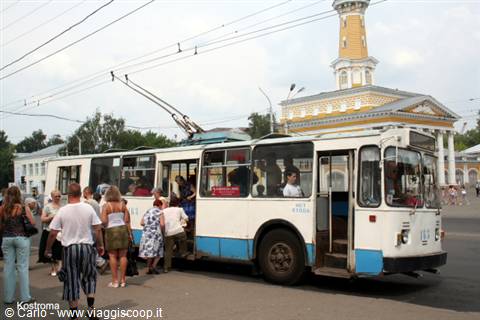 White and blue trolleybus boarding passengers in Kostroma, yellow tower behind
