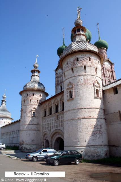 White towers with green domes of Rostov Kremlin, cars parked below