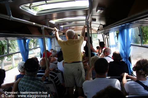 Tourists standing inside a bus with blue curtains, transfer in Pereslavl