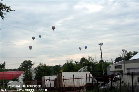 Pereslavl: colorful hot air balloons float above a parking lot among trucks