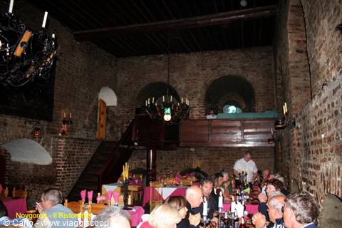 Diners eating in an old brick restaurant hall with wrought-iron chandeliers