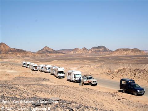 Convoy of motorhomes and SUVs on a dirt road in the Black Desert, Egypt