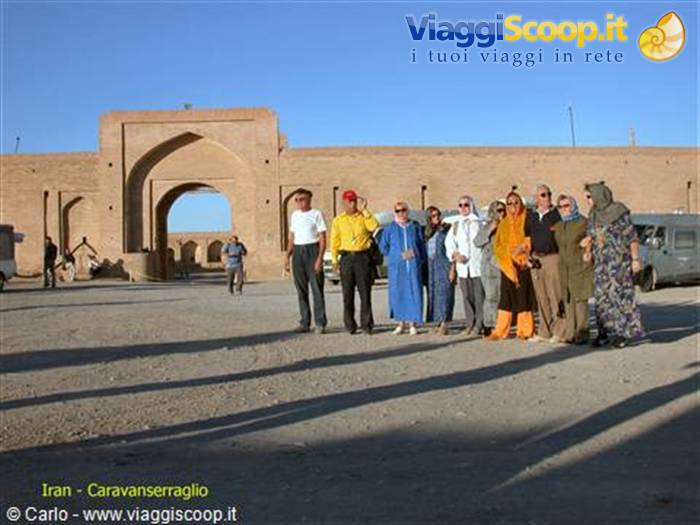 Tourists posing before the mud-brick gateway of Zein-o-din caravanserai