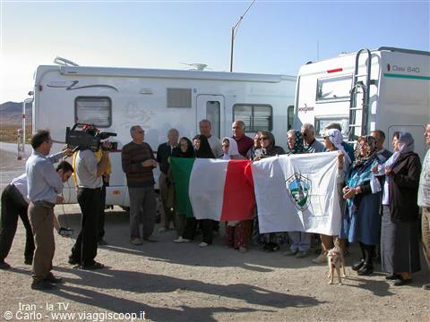 Travelers with Italian flag in front of campervans filming the group