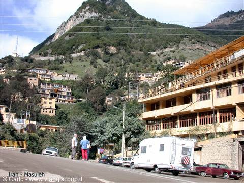 Masuleh, terraced houses on green mountain slope, camper van and tourists on road