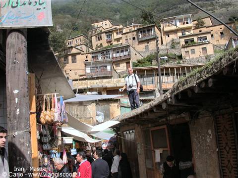 Tourist on wooden rooftop in Masuleh bazaar, brick houses stacked on hillside
