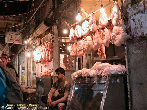 Poultry butcher shop in Tabriz bazaar, hanging meat under glowing bulbs