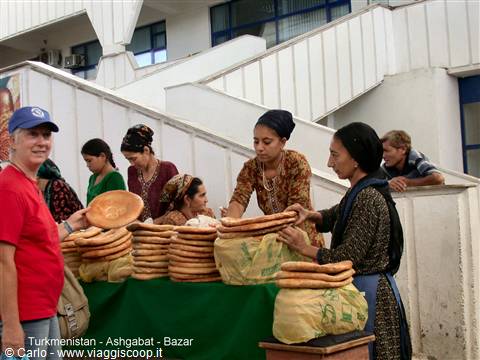 Women selling round bread at Ashgabat bazaar, tourist watching