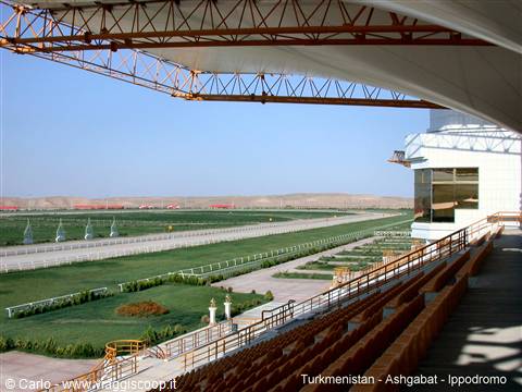 Empty grandstand at Ashgabat hippodrome, white canopy, steel trusses, green track