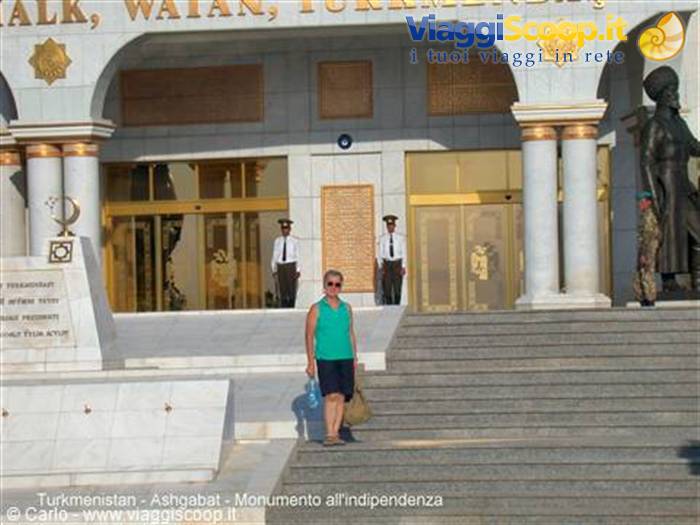 Tourist at the entrance of Ashgabat Independence Monument, uniformed guards standing