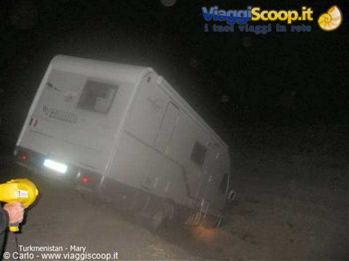 Motorhome tilted on sand at night in Mary, flashlight beam
