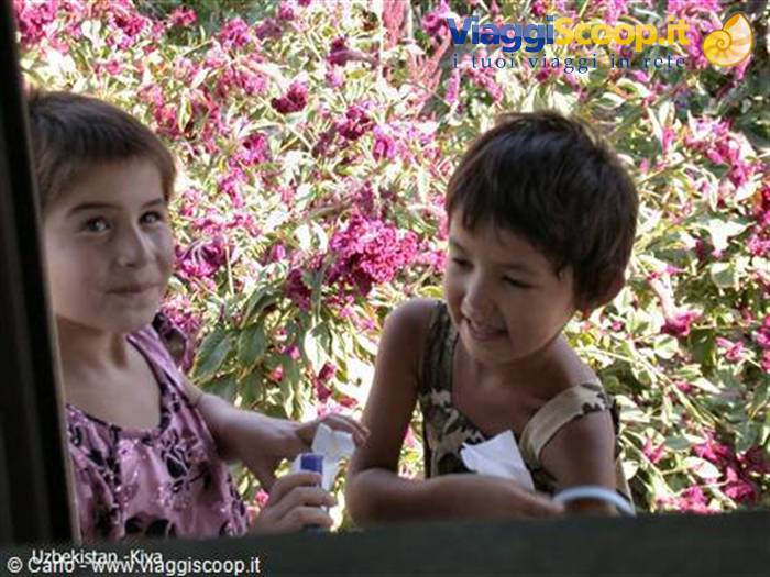 Smiling children at a window among pink flowers in Khiva