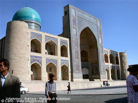 Kukeldash Madrasa in Bukhara, brick and blue tiles, visitors walk in the square
