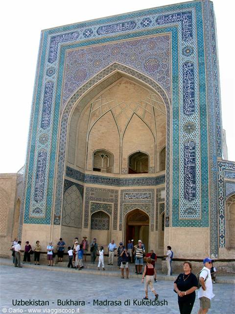 Tourists in front of the blue tiled iwan portal of Kukeldash madrasa, Bukhara