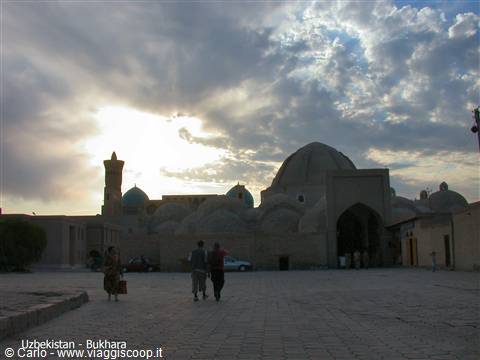 Bukhara: brick domes and minaret under cloudy sky, people walking