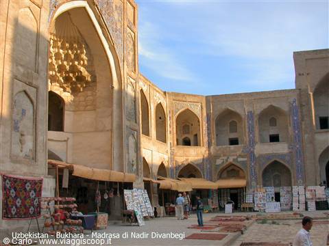 Nadir Divanbegi Madrasa in Bukhara: courtyard with arches, carpets and tourists