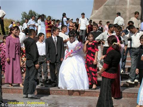 Bride and groom with crowd of guests on the steps in Shakhrisabz