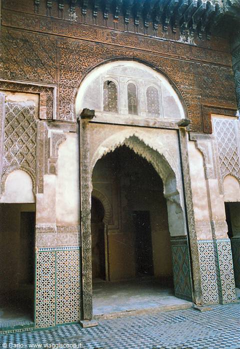 Carved cedar archway with zellige tiles inside the medersa