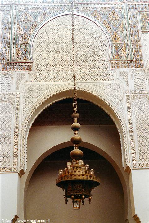 Carved arch with brass chandelier on chain, painted zellige tiles