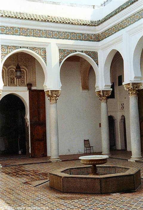 Courtyard with marble fountain, white arches, columns and zellige tiles, natural light