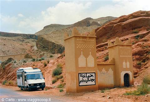 Camper van beside earthen gate towers in the Dadès gorge