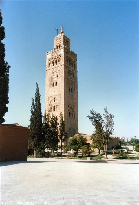 The Koutoubia minaret in Marrakech rises among cypresses under blue sky