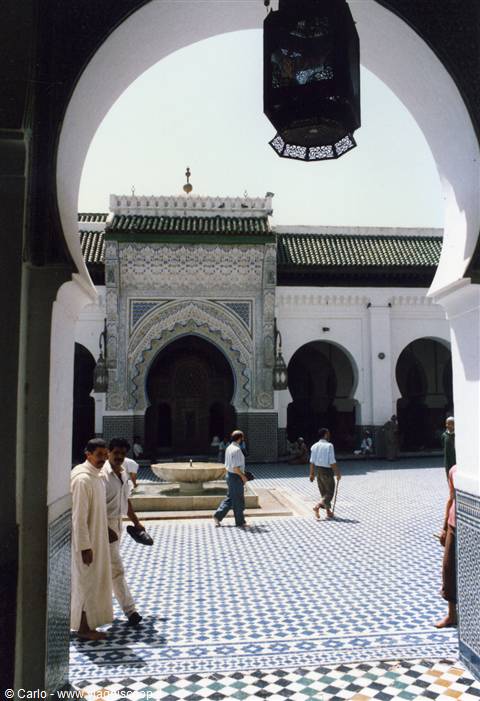 Qarawiyyin mosque courtyard in Fez, zellige tiles, men walking under the arch