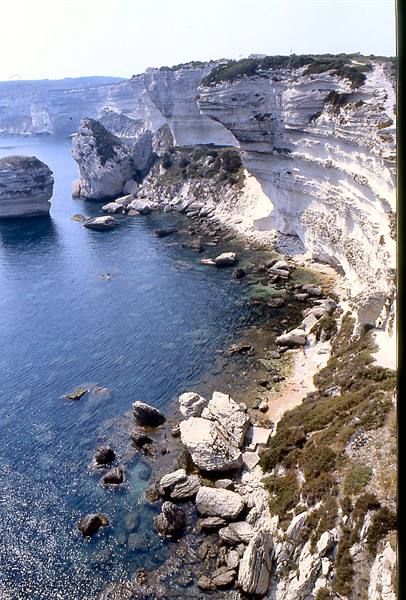 White limestone cliffs over blue sea, scattered rocks and Mediterranean scrub, Bonifacio