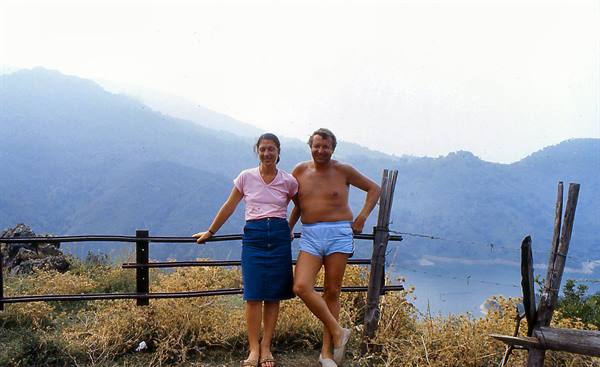 Couple posing by a wooden fence, misty lake and mountains behind