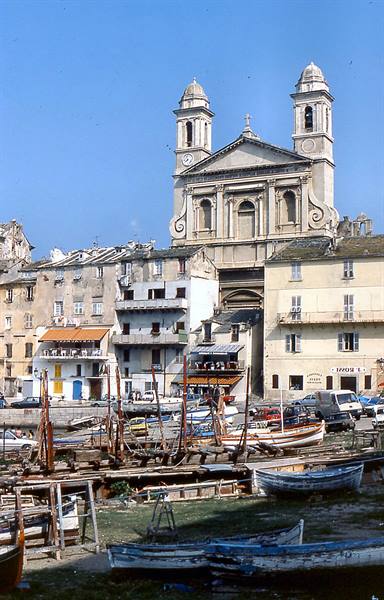 Baroque church with twin bell towers over Bastia old harbour, beached boats