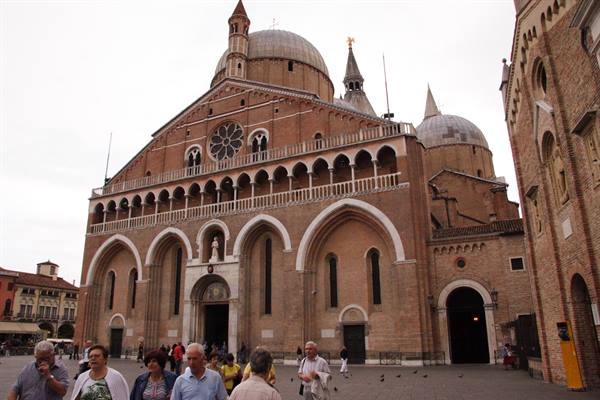Tourists walk in front of the Basilica of Saint Anthony in Padua, cloudy morning