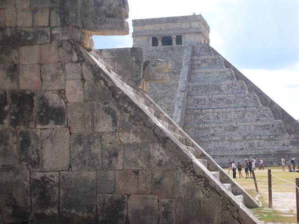 Mayan stone pyramids at Chichén Itzá, tourists walking under morning light
